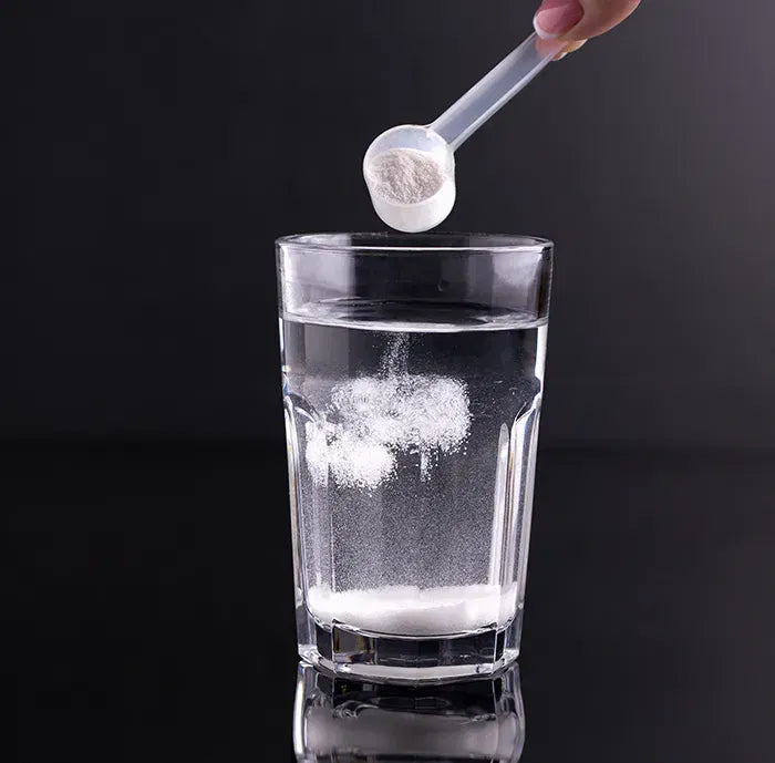 Scoop de creatina disolviéndose en un vaso de agua